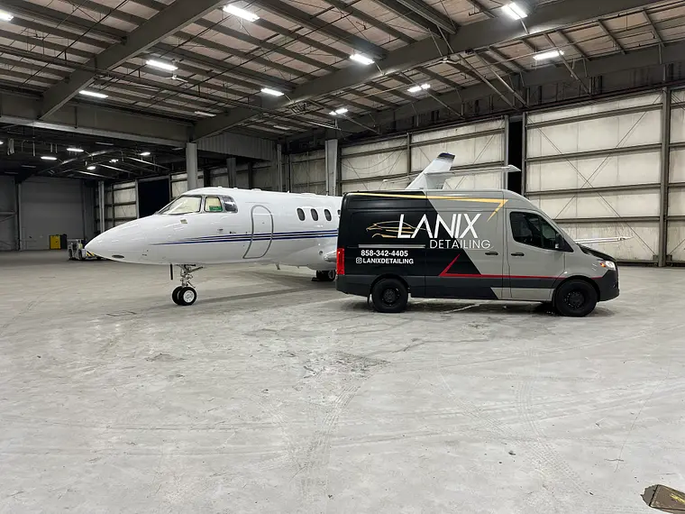 White business jet beside the Lanix van in the hangar