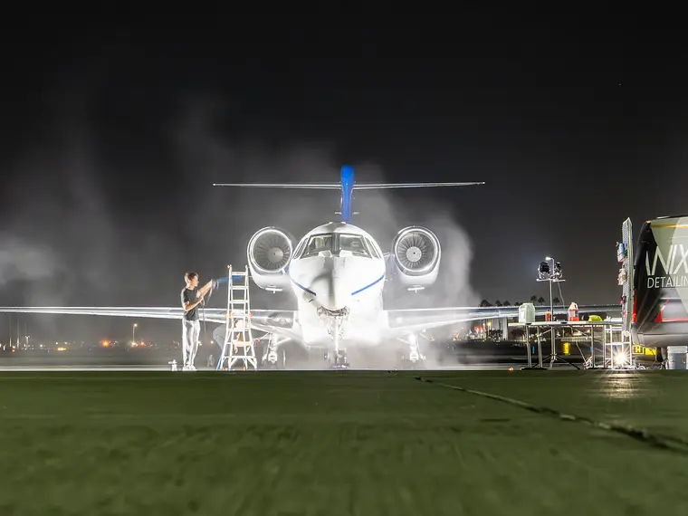 Business jet head-on at night during an exterior wash