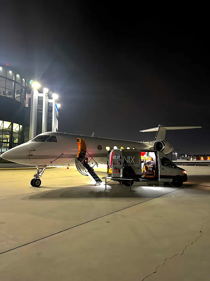 Business jet and Lanix van on the ramp at night beside the terminal