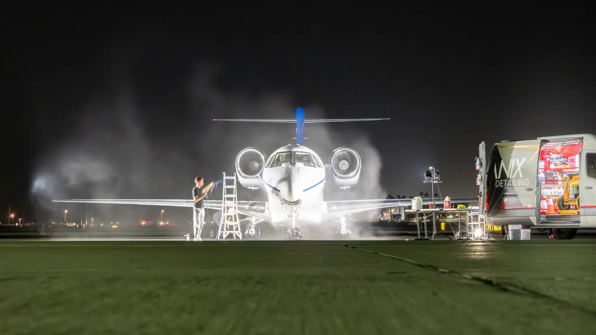 Business jet washed at night on the ramp beside the Lanix Detailing van